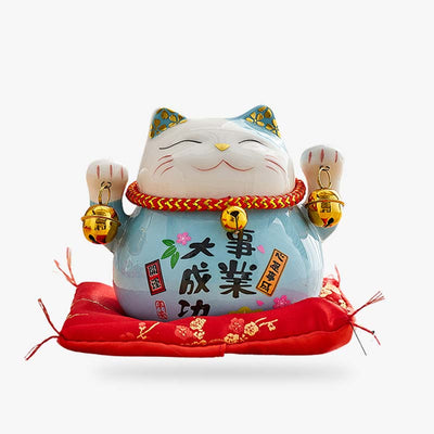 Cette statuette est un chat maneki neko bleu qui tien des clochettes dans ses deux pattes levées. La statuette de chat japonais est en céramique avec des kanji dessinés de couleur noir