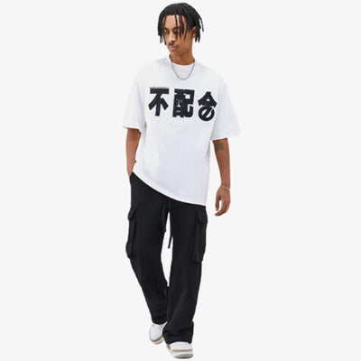 UN homme avec un pantalon noir pense acheter un t-shirt coton motif japonais.