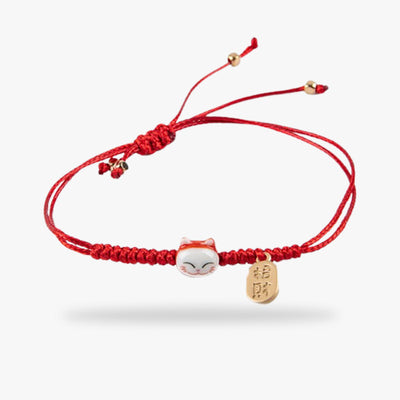 Un bracelet chat japonais avec un fil de couleur rouge une petite tête de chat maneki neko