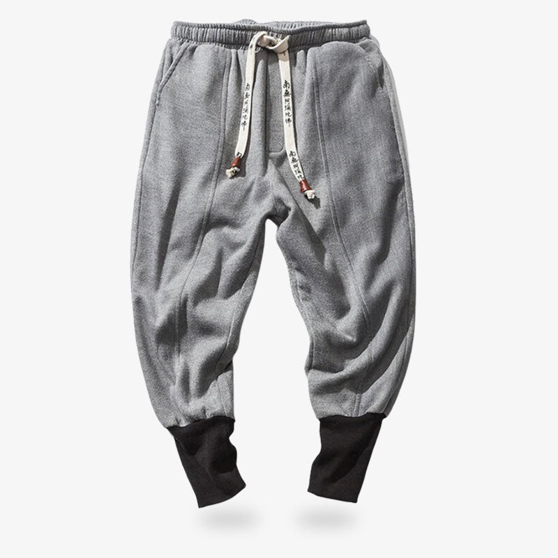 Ce jogging ninja est de couleur gris, et resserré au niveau des chevilles. Ce pantalon japonais est de couleur gris. Le cordon avec des imprimés de kanji japonais sert le vêtement au niveau de la taille