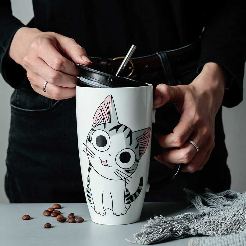 Une femme tient dans les mains un kawaii cat mug avec une paille