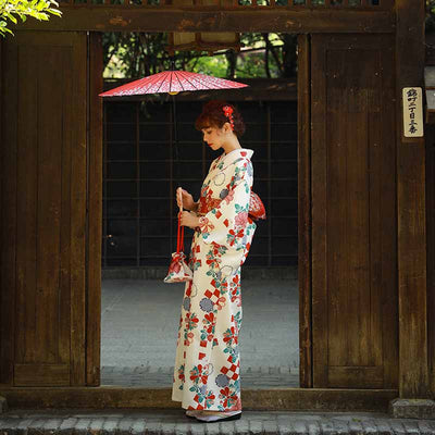 Un kimono traditionnel japonais pour femme qui est élégant en blanc avec des motifs de fleurs sakura et fukiwa. La femme tient une ombrelle japonaise, rehaussant sont style de geisha magnifique