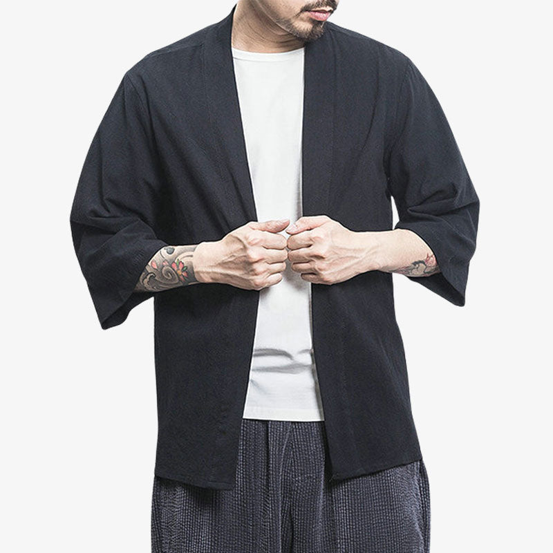 Un homme est habillé avec un t-shirt blanc et un long kimono cardigan de couleur noire. La matière est en coton et en lin. C'est un style de vêtement japonais homme qui se porte par dessus un kimono ou yukata