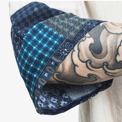 Un homme avec un tatouage japonais sur l'avant bras montre la manche de son kimono cardigan court de couleur blanche. Le tissu de la manche est imprimé avec des symboles japonais de forme géométriques