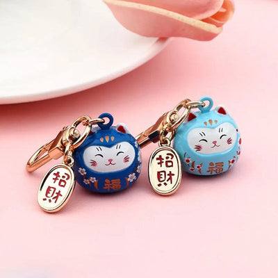 Ce porte-clé maneki neko est en forme de chat japonais. Les deux chat maneki neko sont décorés avec des peintures de fleurs de sakura et des kanji. La partie metallique en laiton de cet accessoire japonais est gravée avec un kani qui signifie: la bonne fortune