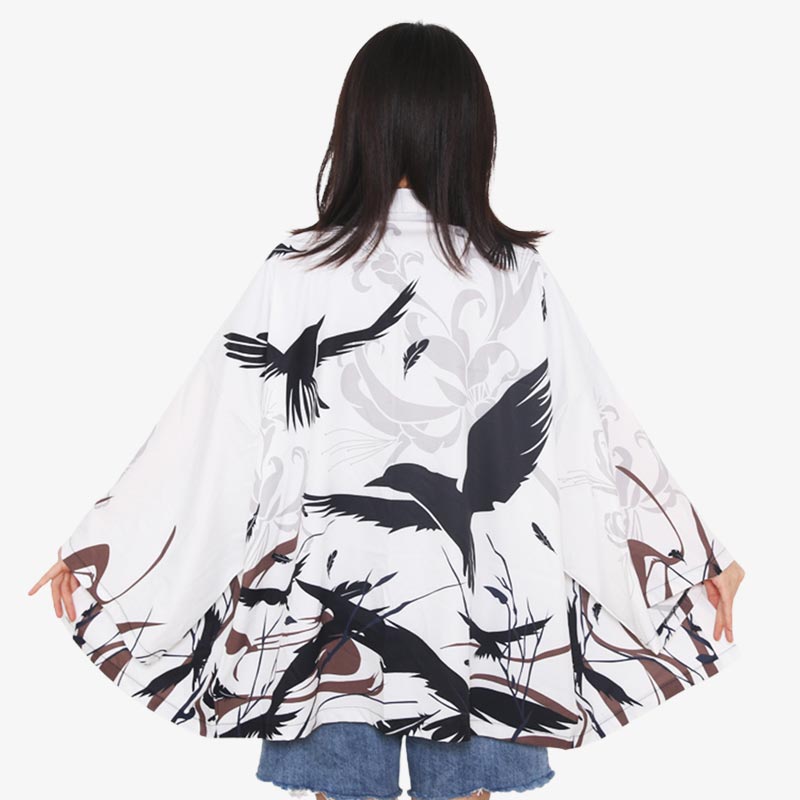 Une fille est habillée avec une veste kimono japonais court pour femme. Le tissu en coton blanc est imprimé avec un motif de corbeaux noirs