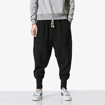 Un japonais porte un pantalon streetwear homme avec des baskets sneakers blanches et un pull manches longues de couleur gris