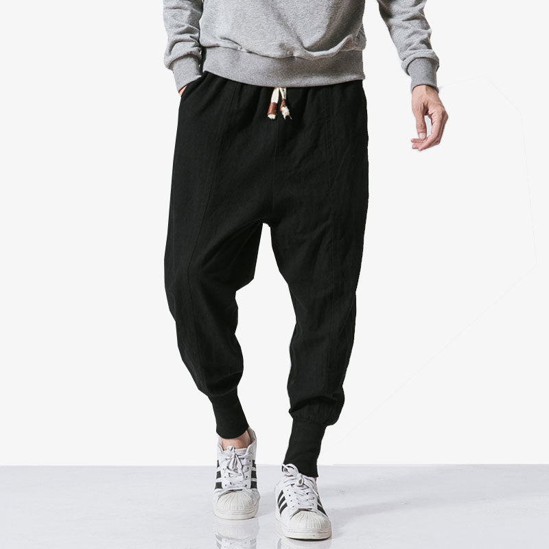 Un homme porte un pantalon streetwear avec des sneakers adidas et un sweatshirt gris