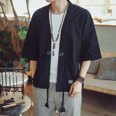 Une veste haori pour homme enfilé par dessus un tee-shirt blanc. L'homme porte un pantalon cargo gris et des bijoux sur les mains et poignets